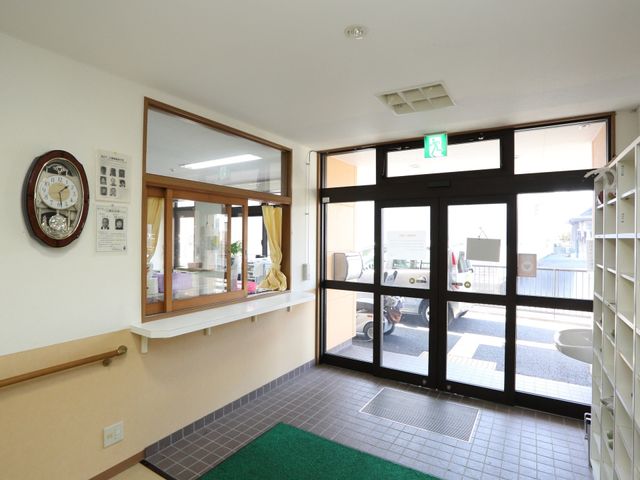 入口付近の明るい廊下 玄関 広々とした入り口は明るく、移動しやすい設計で、心地よい出迎えが可能です。壁には掲示物があり、情報共有も行える設備が整っています。