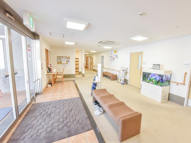 明るく広々としたエントランス 玄関5 エントランスはゆったりとしており、訪れる方々の心を和ませるアクアリウムが配置されています。清潔感のある雰囲気で、皆様をお迎えいたします。