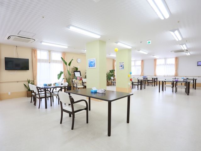 広々とした明るい食堂 共有スペース ゆったりとした食堂では、居心地の良い環境で職員と共に食事の時間を過ごせます。大型テレビが設置されており、リラックスして情報も得られる空間です。