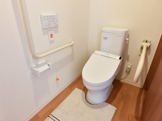 バリアフリートイレ 個室トイレ 手すり付きの清潔なトイレは、安心してご利用いただける設計です。床材には暖かみのある木目調を採用しており、温もりを感じられる空間になっています。