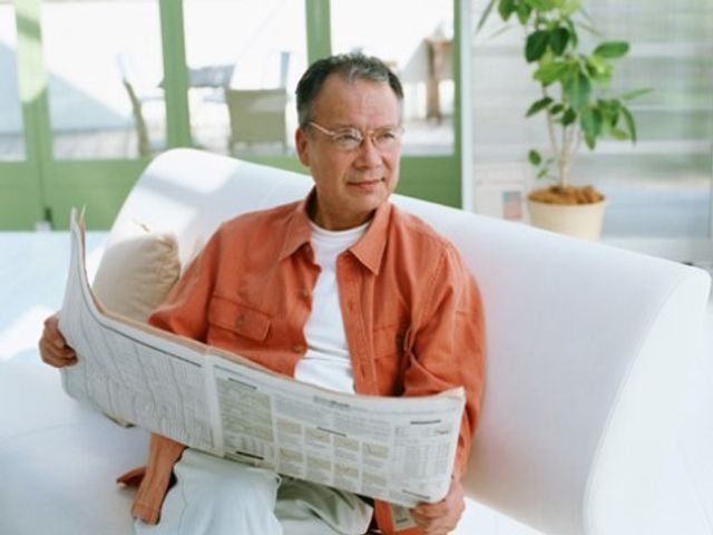 リラックスした男性とソファ 入居者様 快適なソファで新聞を楽しむ落ち着いた雰囲気のラウンジ。ゆったり過ごせる場所で働いてみませんか。
