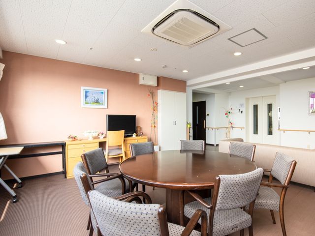 円卓と椅子のある明るい部屋 談話室 ゆったりとした空間で憩いの場を提供しており、円卓を囲んでコミュニケーションが取れます。