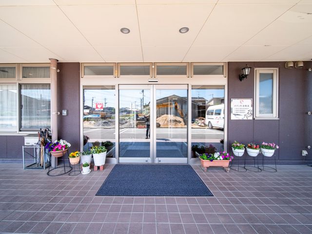 明るいエントランスの風景 玄関 色とりどりの花が迎える入口は、訪れる人に温かい印象を与えています。