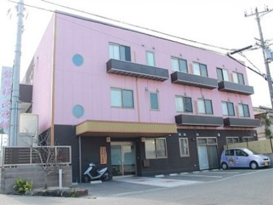 ピンク色の外壁と丸い窓が特徴的な３階建ての施設は、玄関が老舗旅館を思わせおしゃれな造りになっている。