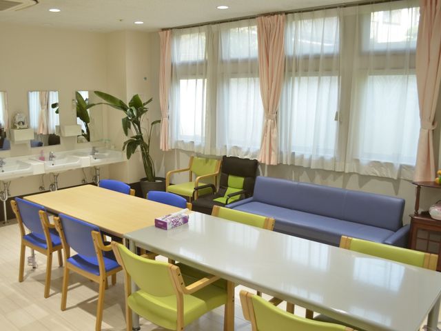 広々とした明るい居室 共有スペース ゆったりとしたソファや椅子が配置された空間で、穏やかな時間を過ごすことができます。窓からは自然光が差し込み、温かな雰囲気を醸し出しています。