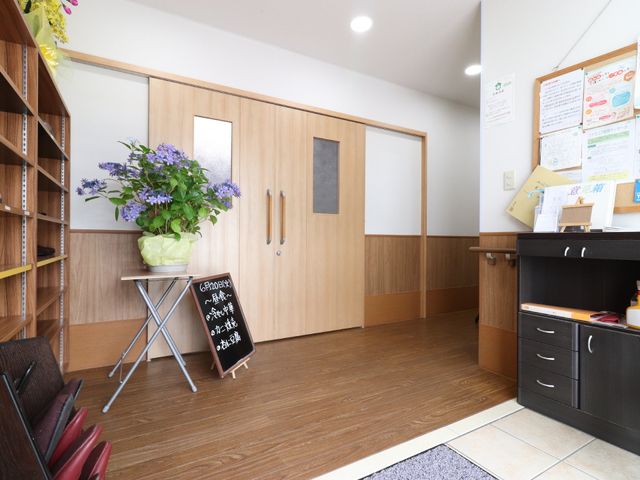 エントランスに花と掲示板 玄関 温かみのあるエントランスは、来訪者を優しく迎え入れます。情報掲示も行き届き、安心の環境を提供しています。