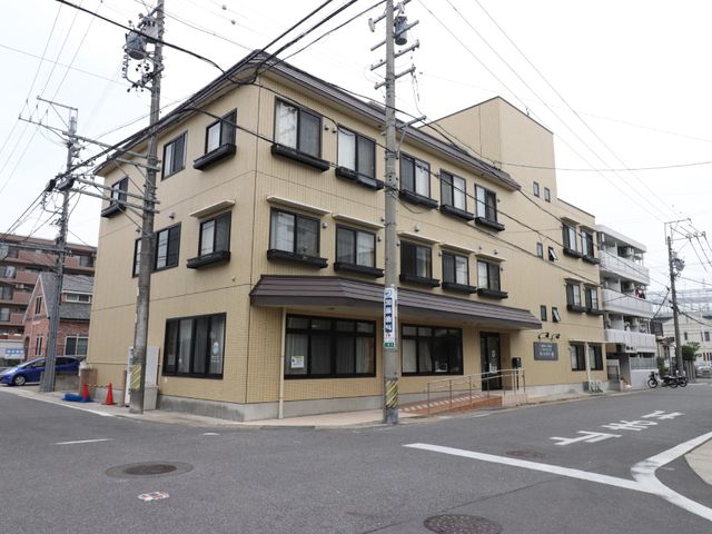 黄色い建物の外観 外観 落ち着いた色合いの外観を持つ建物で、アクセスしやすい平坦な道路に面しています。清潔感のあるエントランスが皆様をお迎えします。