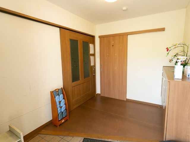 清潔な居室入口 玄関 温かみのある木製ドアが迎える居室、普段使いの備品が整っています。