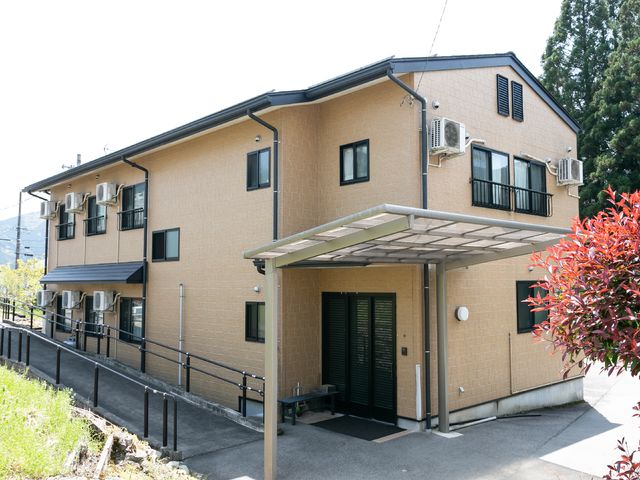 落ち着いた色の建物外観 外観 暖かみのある外壁が印象的な建物です。手すり付きのアプローチが安心感を与えます。