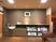 サムネイル 施設の写真 談話室には、棚にいくつかの大判の本が置いてある。左側には電気ポッドや飲み物用のコップがまとめられている。
