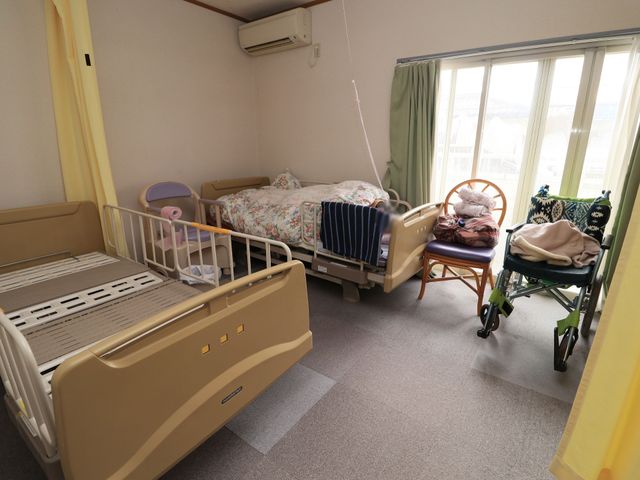 居室内の明るい情景 居室 ぬくもりを感じる個室で、窓からは自然光がたっぷりと差し込んでいます。機能的なベッドや車椅子が整っており、快適な生活空間が確保されています。