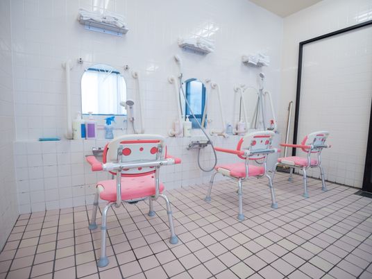 洗い場が３つ設置され、手すり付きのシャワーチェアーも各台に置かれている。壁には左右に手すりがあり、安全に利用できる。