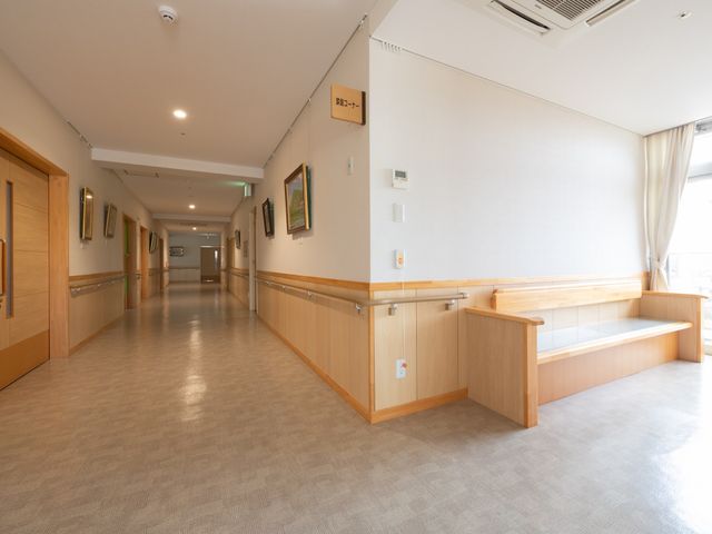 清潔な廊下 廊下 ゆったりとした通路には、壁に飾られた絵画がアクセントになっています。休憩に便利なベンチも設置されており、居心地の良い雰囲気が漂っています。