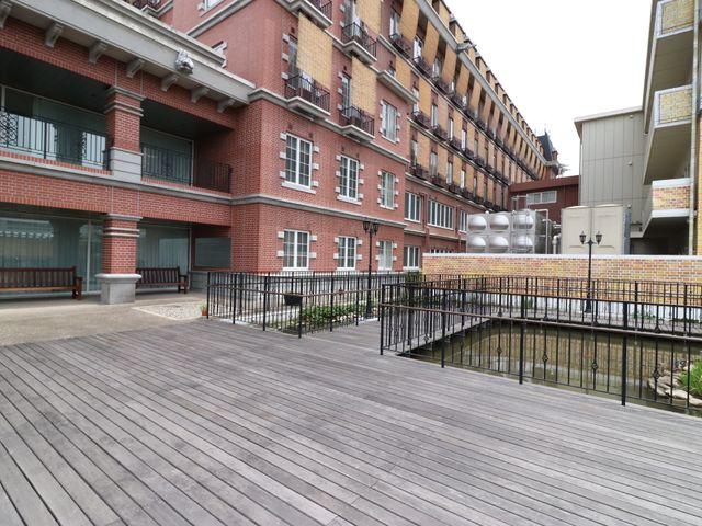 中庭のデッキと建物 蓮池 ゆったりとした木製のデッキが広がり、建物を囲む中庭は心地よい休息の場を提供しています。安全を考慮した手すりも設置され、散策にも最適です。