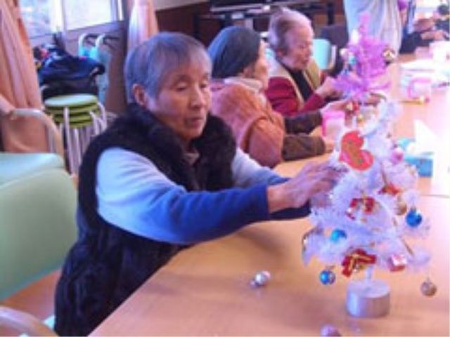 居住者がクリスマスツリー飾り付け イベント 居住者が楽しげにクリスマスツリーの飾り付けをしている様子です。共に時間を過ごしながら、季節のイベントを楽しむひと時を提供しています。