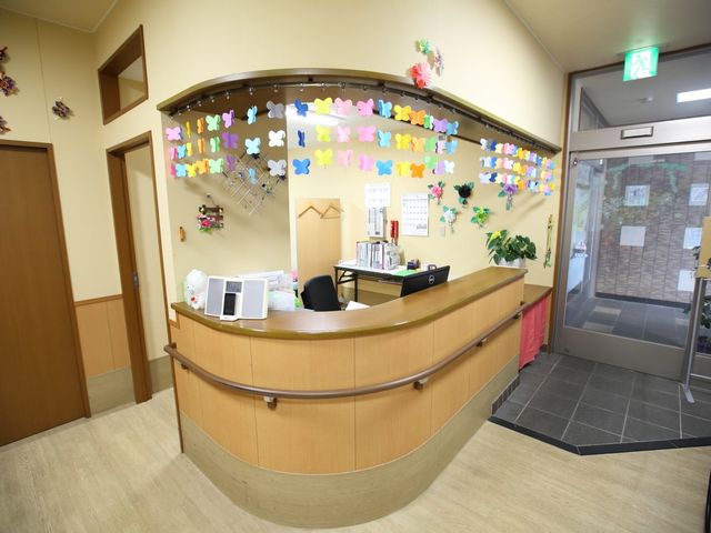 カラフルな装飾のフロント 受付 木目調の温かみのあるフロントで、明るく色とりどりな装飾がお客様を迎える様子です。快適な職場環境を考慮した空間は、日々の業務に役立ちます。