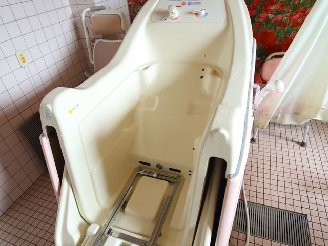 設備充実した浴室 特殊浴室 機能的な浴槽が設置され、安全かつ快適にお使いいただける空間です。壁には花畑を思わせる明るい壁紙が貼られており、心地よいバスタイムを支えます。