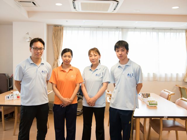 笑顔の職員4名と明るい空間 専門スタッフ 明るい空間で笑顔を見せる職員たち、チームワークの大切さが感じられます。