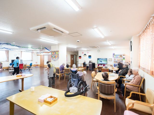 明るい共有スペースの様子 共有スペース ゆとりある食堂では、利用者様がお食事や憩いの時間を過ごされています。椅子に座る方や車椅子の方が共にくつろいでいらっしゃる光景が見受けられます。