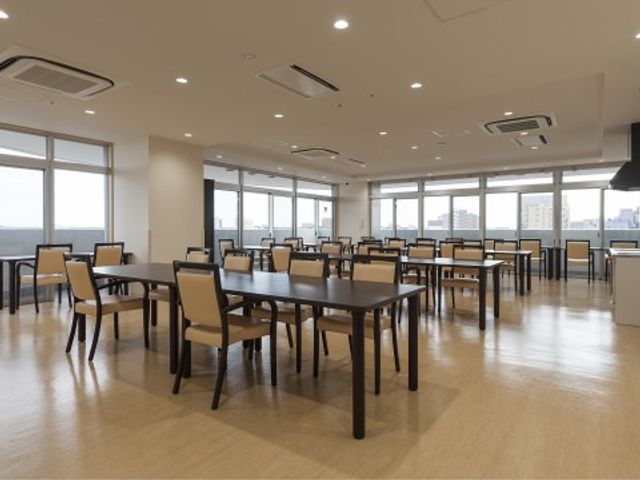 明るい食堂の風景 食堂 広々とした空間で、日差しが注ぐ清潔感あるダイニングです。落ち着いた色合いの家具が配置され、温かみのある雰囲気が漂います。