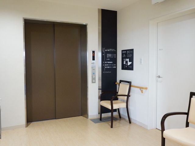 エレベーターと掲示物のある廊下 エレベーター 清潔感のあふれる廊下は、動線もしっかり確保されています。ゆとりのある空間で快適な勤務が期待できます。