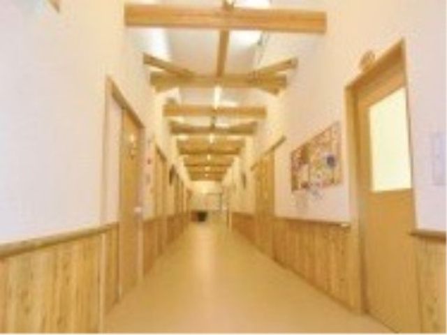 明るい木目調の廊下 廊下 温かみのある木の素材が印象的で、さまざまな掲示物が訪れる人を迎えています。