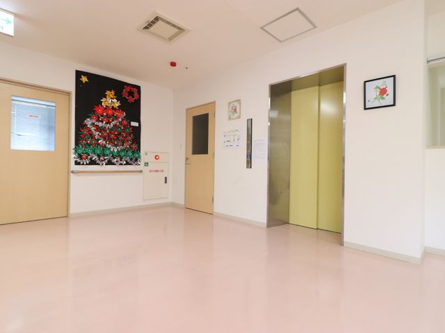 廊下に飾られたクリスマスツリー エレベーターホール 季節感のあふれる装飾が施された明るい廊下です。このような温かみのある環境で、ご利用者と接することができます。