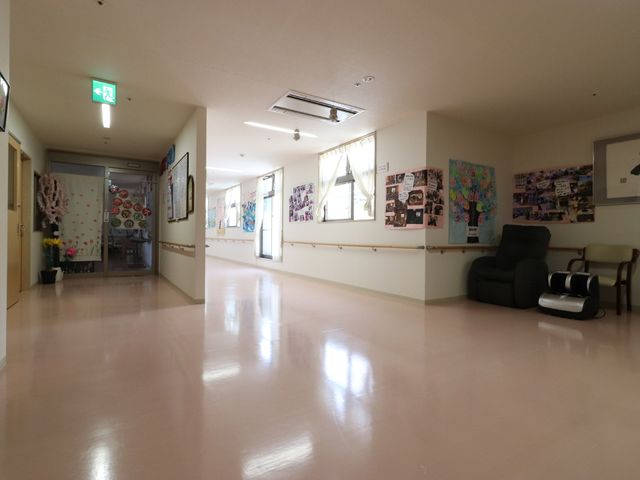 明るく清潔な廊下 廊下 壁に飾られた色とりどりの掲示物が、廊下を温かみのある空間へと変えています。休憩スペースには、リラックスできるマッサージチェアが備わっております。