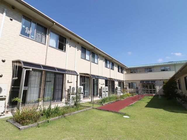 明るい施設の外観 中庭 広々とした緑あふれる環境で、心地よい日々を過ごせる場所です。新たな職場としても、居心地の良さを感じていただけるでしょう。