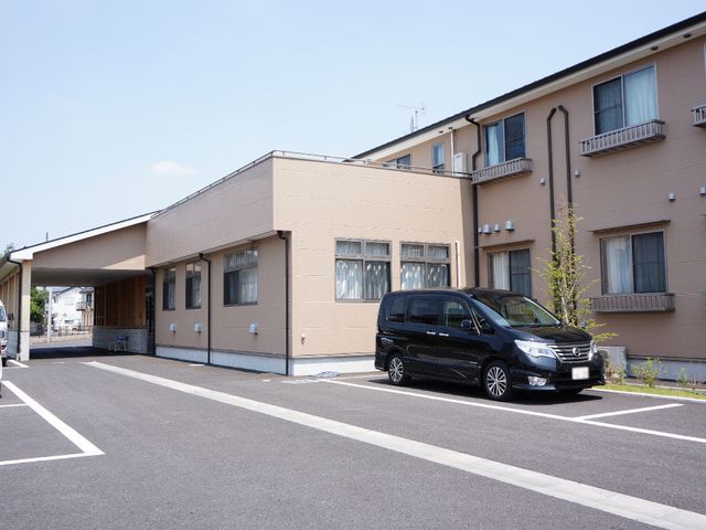 施設の外観と駐車場 施設外観正面 ゆとりある駐車スペースを備えた外観です。来訪される皆様のアクセスが便利であることを示しています。