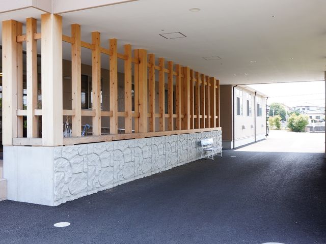 木の柱が特徴のエントランス 施設正面玄関 広々としたエントランスは自然の光がたっぷりと入り、待ち合わせや一息つくのに適した空間があります。ここでのひとときが、毎日の活力につながるでしょう。