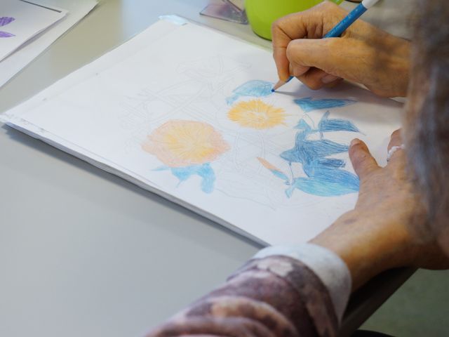 多目的室での趣味活動 訓練室 手に鉛筆を持ち、集中してお絵描きに取り組む方の姿が見られます。創造性を発揮できる環境でご自身の時間を大切にできます。