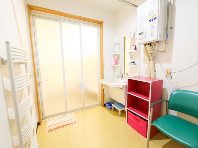 洗面台と看護備品の居室 脱衣所 清潔感のある居室には、利用者の快適さを考えた洗面設備が整っています。明るく安心できる環境で、毎日の身の回りのお世話をサポートします。