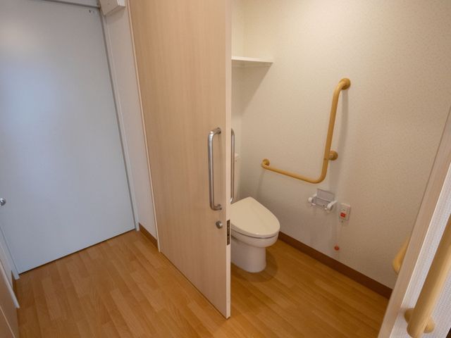 手すり付きトイレ空間 トイレ 安全性に配慮したトイレは、手すりが完備され、イエローカラーが視認性を高めています。周辺は清潔感があり、落ち着いて利用できる設計です。