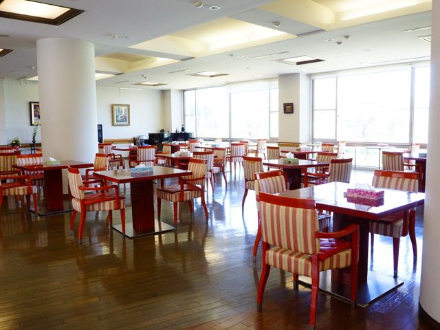 広々とした快適な食堂 食堂 ゆったりとした配置で、木目のテーブルと赤い椅子が並ぶ明るい食堂です。窓からは自然光が差し込み、居心地の良い食事の時間を提供します。