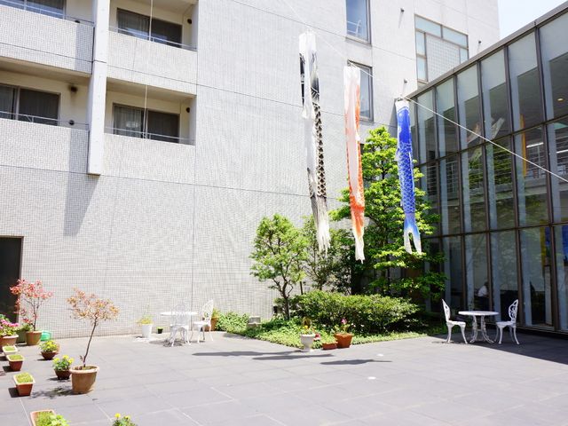 中庭の鯉のぼりと植物 外観 日当たりの良い中庭では、彩り鮮やかな鯉のぼりが風に揺れています。周りに配された植物たちが季節の移り変わりを感じさせる空間です。