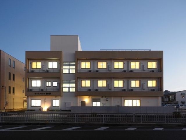 夕暮れ時の清潔な外観 外観 夕刻に照らされた建物が温かみを放ち、きれいに灯された室内からは安らぎの空間が感じられます。新しい職場として、穏やかな雰囲気の中でのお仕事をご検討ください。