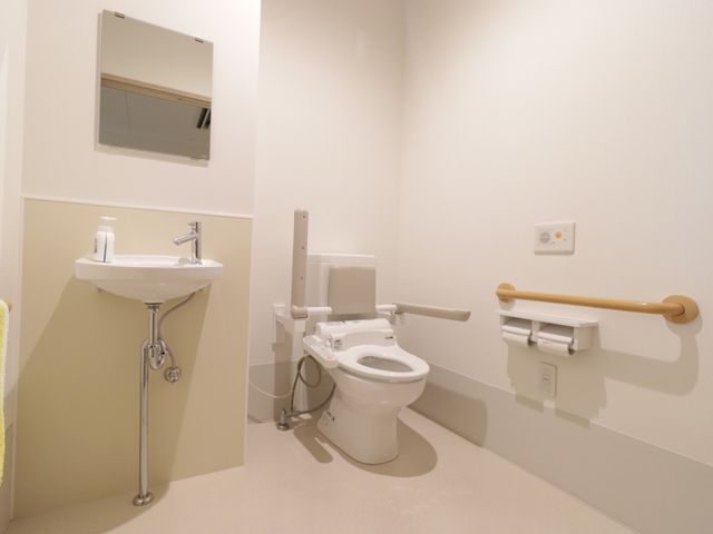 バリアフリーなトイレ空間 トイレ 手すり付きで安全に配慮された清潔なトイレです。利用者の快適性に気を配った設計がされています。