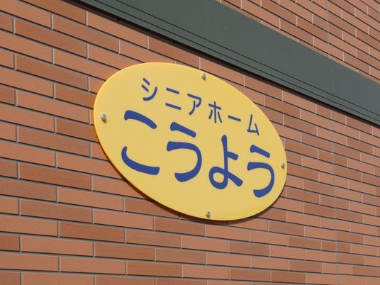 レンガ造りのモダンな建物の壁に施設名の書かれた看板が掲げられている。青い文字で大きくはっきりと書かれてある。