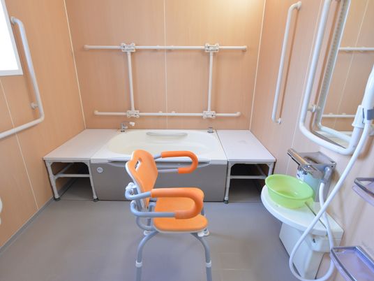 介護椅子が設置されたお風呂。壁には手すりが設置されている。サーモスタット混合栓のシャワーが設置されている。
