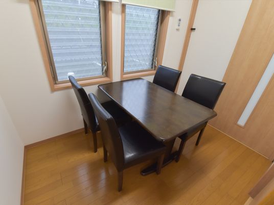 窓辺にダークブラウンのテーブルと黒の皮張りの椅子が置かれた落ち着いた雰囲気のプライベートタイプの談話室。