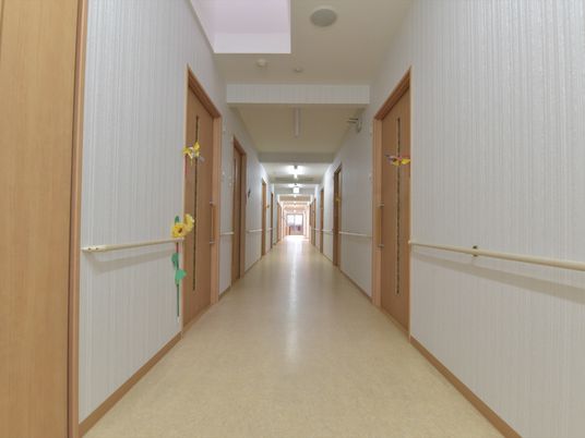 ベージュ系で統一されている掃除が行き届いた清潔感のある廊下。真っ直ぐに伸びた廊下の両サイドに手すりが設置されている。