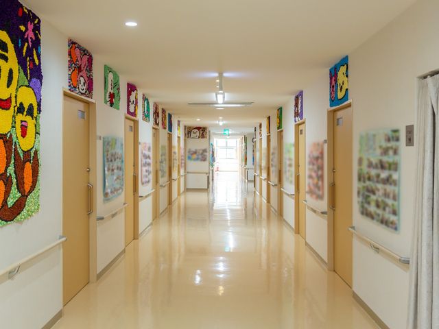 カラフルな壁飾りの廊下 通路 廊下には明るい色彩の壁飾りが飾られ、温かみのある雰囲気を醸し出しています。清潔感のある床と合わせ、快適な通行スペースが確保されています。