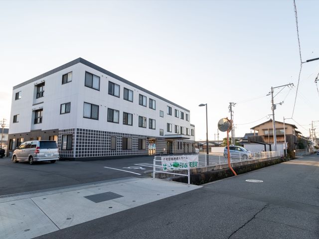 白い建物の外観写 外観 広々とした駐車場がある清潔感のあるモダンな建物です。通勤に便利な立地環境を備え、快適な就業が期待できます。