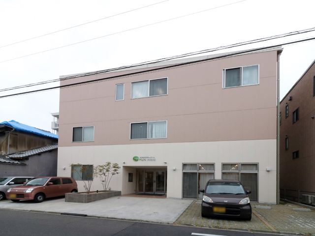 清潔なピンク色の建物外観 駐車場と乗降スペース 落ち着いた色合いの外壁が特徴の建物で、スタッフと共に働くことで多く学びが得られそうです。