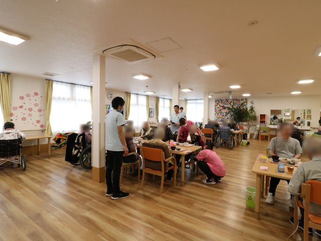 居室内の日常風景 リビング・ダイニング 広々とした明るい食堂では、利用者様が食事を楽しんだり、スタッフが丁寧にサポートしています。