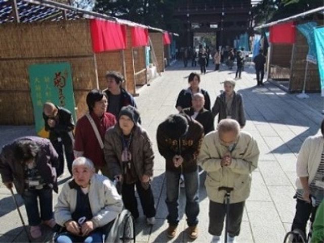 集団での屋外活動 お寺 温かな日差しの下、利用者の方々と共に活動を行っており、寄り添いながら支援する姿が垣間見えます。スタッフとしてもやりがいを感じられる光景です。