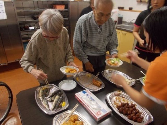 食事の様子料理提供中 バイキング 明るい雰囲気で食事を配膳している様子です。様々な料理を自由に選べるスタイルで、利用者の方の食事時間が充実しています。