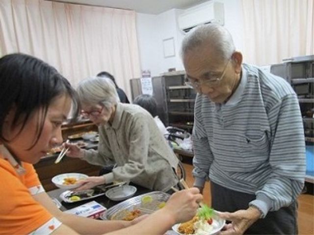 食事のサポート風景 バイキング 優しい手つきでお食事のお手伝いをしている風景です。共に食事を楽しむ姿から温かい雰囲気が感じられます。