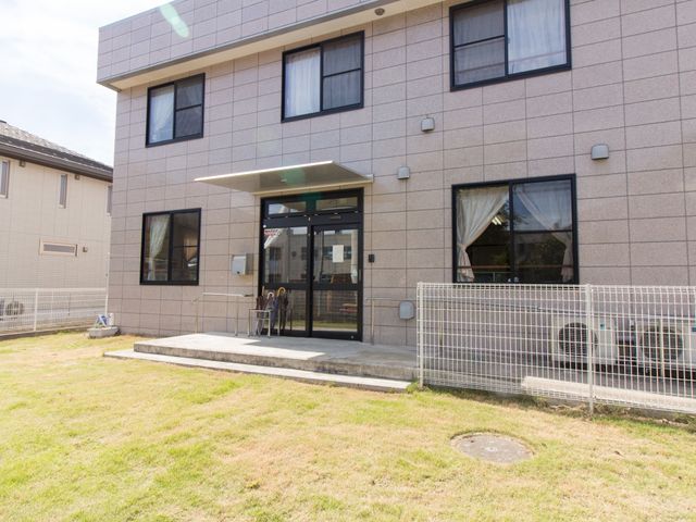 明るい外観の建物入口 外観 庭が見える清潔感のあるエントランス。バリアフリー設計で安全性に配慮した入り口です。